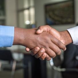 Two people shaking hands while closing a business deal between companies.